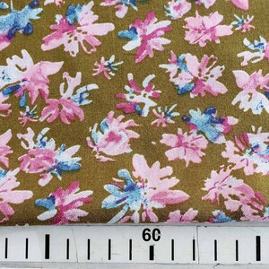 Pu&ograve; includere: Primo piano di un tessuto con sfondo marrone e un motivo ripetitivo di fiori rosa e blu. Il tessuto &egrave; misurato con un righello che mostra 30 e 60.