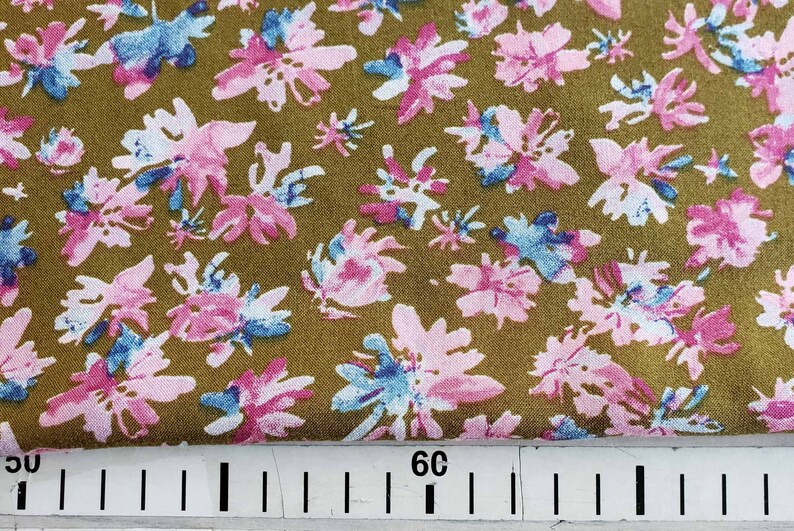 Pu&ograve; includere: Primo piano di un tessuto con sfondo marrone e un motivo ripetitivo di fiori rosa e blu. Il tessuto &egrave; misurato con un righello che mostra 30 e 60.