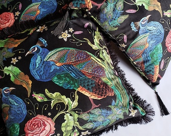 May include: Two black velvet throw pillows with embroidered peacocks and floral designs. The pillows have black fringe trim and tassels.