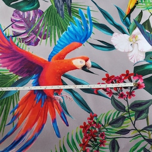 May include: A colorful tropical fabric featuring a red and blue parrot with green and purple leaves. The fabric also features a white orchid and a hummingbird.