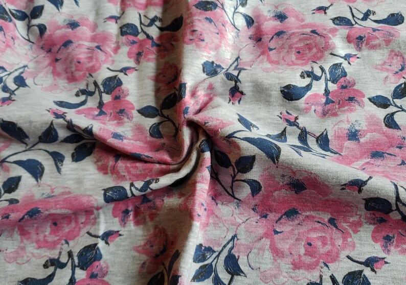May include: Gray fabric with a pink floral print. The fabric has a soft, textured feel and is perfect for crafting projects.
