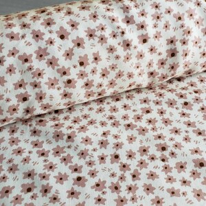 Pu&ograve; includere: Tessuto bianco con un motivo floreale rosa. I fiori sono piccoli e sparsi sul tessuto.