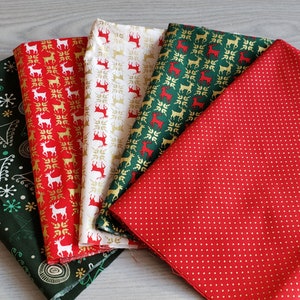 K&ouml;nnte beinhalten: F&uuml;nf verschiedene Stoffmuster mit Weihnachtsmotiven. Die Stoffe sind in den Farben Rot, Gr&uuml;n, Wei&szlig; und Gold gehalten. Ein Stoff hat einen roten Hintergrund mit wei&szlig;en Punkten, ein anderer einen gr&uuml;nen Hintergrund mit wei&szlig;en Schneeflocken und Kreisen, und die restlichen drei Stoffe haben einen wei&szlig;en Hintergrund mit roten und goldenen Rentiermustern.