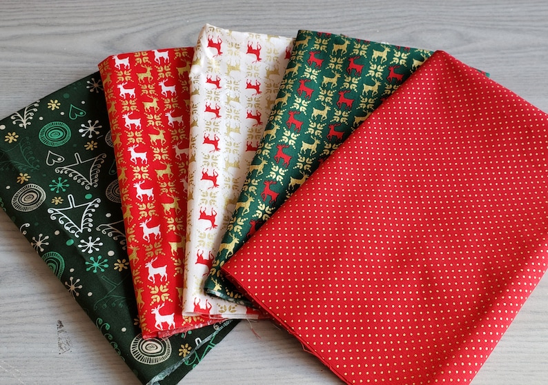 K&ouml;nnte beinhalten: F&uuml;nf verschiedene Stoffmuster mit Weihnachtsmotiven. Die Stoffe sind in den Farben Rot, Gr&uuml;n, Wei&szlig; und Gold gehalten. Ein Stoff hat einen roten Hintergrund mit wei&szlig;en Punkten, ein anderer einen gr&uuml;nen Hintergrund mit wei&szlig;en Schneeflocken und Kreisen, und die restlichen drei Stoffe haben einen wei&szlig;en Hintergrund mit roten und goldenen Rentiermustern.