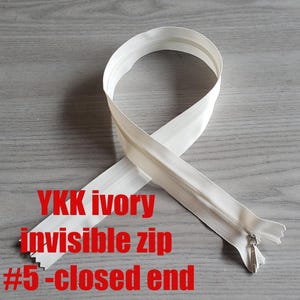 以下が含まれることがあります： 閉じた端を持つ、白いYKKアイボリーインビジブルジッパー。ジッパーは#5サイズです。
