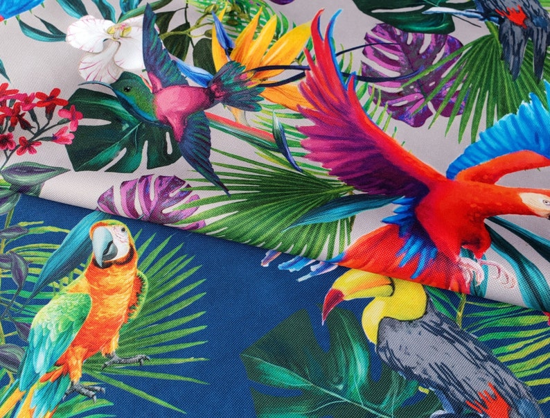 May include: A colorful fabric with a tropical print featuring parrots, hummingbirds, and lush green foliage. The fabric has a white background with a blue section at the bottom.