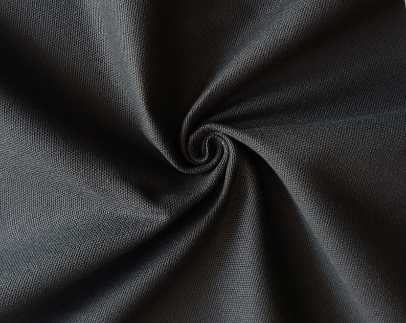 Puede incluir: Primer plano de una tela gris oscuro con un tejido texturizado. La tela est&aacute; doblada y drapeada, creando un aspecto suave y fluido.
