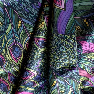 May include: A colorful fabric with a peacock feather pattern. The fabric is a dark blue with green, pink, and yellow accents. The feathers are detailed with intricate designs.