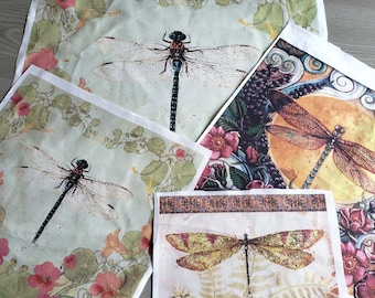 May include: Four fabric squares with dragonfly designs. Each square features a different dragonfly with varying colors and patterns. The dragonflies are surrounded by floral and leafy designs.