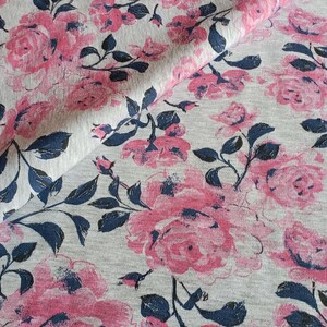 May include: Gray fabric with a pink and blue floral print. The fabric features a repeating pattern of roses and leaves.