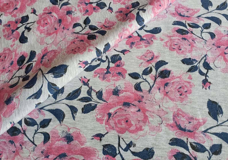 May include: Gray fabric with a pink and blue floral print. The fabric features a repeating pattern of roses and leaves.