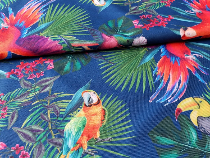 May include: A blue fabric with a tropical print featuring parrots, toucans, and palm leaves. The parrots are red, orange, and green, and the toucans are yellow and black.