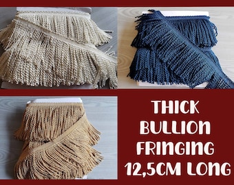 Può includere: Tre rocche di frange spesse in colori crema, blu navy e oro. Ogni bordo presenta una fascia tessuta con lunghi fili di corda ritorti che pendono verso il basso. Il testo sull'immagine recita: THICK BULLION FRINGING 12,5CM LONG.