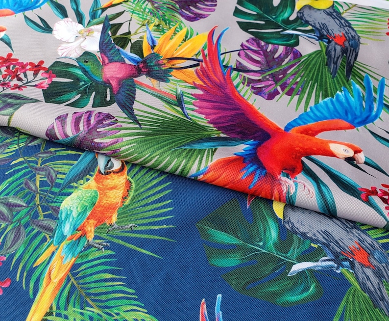 May include: A colorful fabric with a tropical print featuring parrots, toucans, and lush green leaves. The fabric has a blue background with a gray and white pattern.