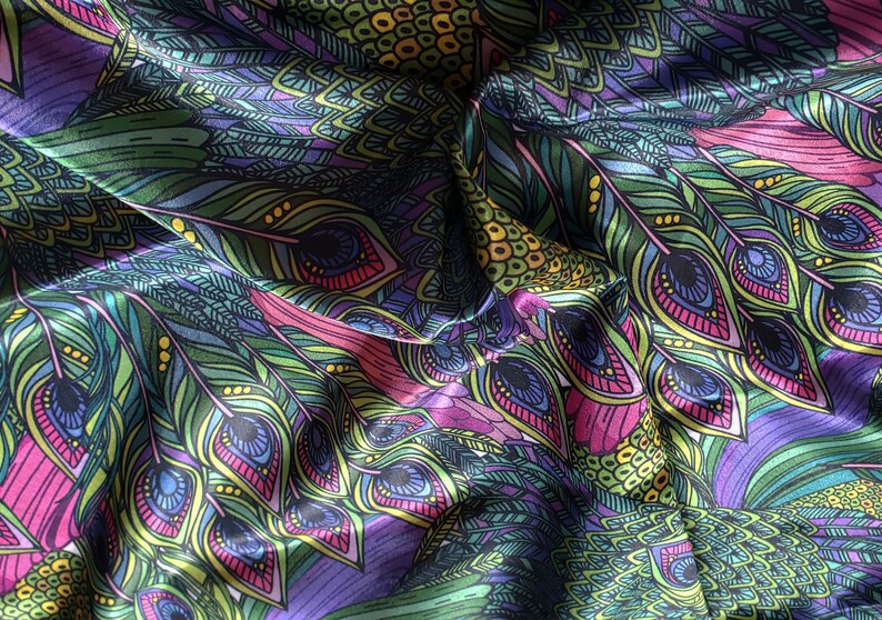 May include: A close-up of a fabric with a peacock feather pattern. The fabric is a mix of green, purple, pink, and yellow colors. The feathers are detailed with intricate designs.