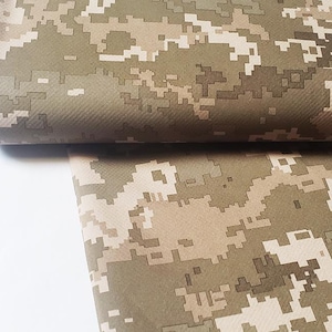 May include: Close-up of a folded fabric with a pixelated camouflage pattern in shades of green, brown, and tan. The fabric is tightly woven and appears to be durable, suitable for various applications.