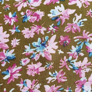 Pu&ograve; includere: Un tessuto marrone con un motivo ripetitivo di fiori stilizzati rosa, blu e bianchi. I fiori sono astratti e hanno un aspetto acquerellato.