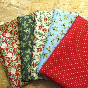 K&ouml;nnte beinhalten: F&uuml;nf Stoffmuster mit Weihnachtsmotiven. Die Muster sind rot, gr&uuml;n, blau, wei&szlig; und gold. Die Muster umfassen Stechpalmenbl&auml;tter, Weihnachtssterne und Punkte.