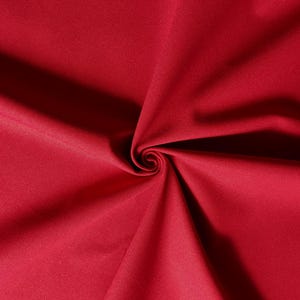 Puede incluir: Primer plano de una tela de color rojo intenso con una textura lisa. La tela est&aacute; doblada de forma que crea un patr&oacute;n de espiral.