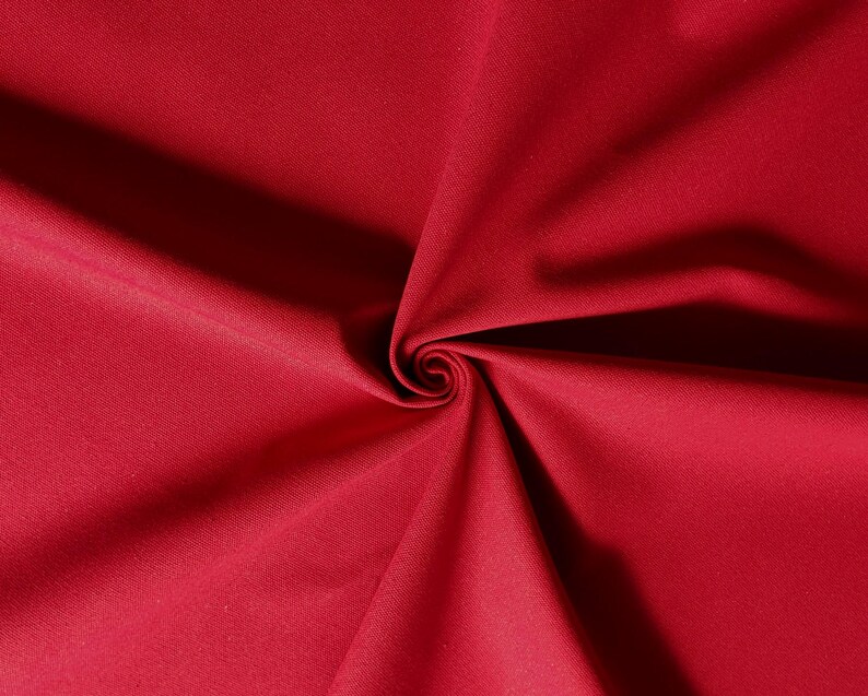 Puede incluir: Primer plano de una tela de color rojo intenso con una textura lisa. La tela est&aacute; doblada de forma que crea un patr&oacute;n de espiral.