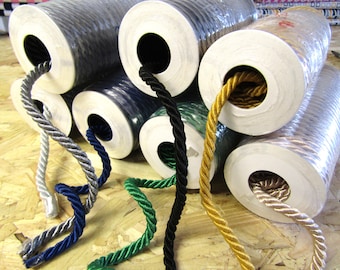 May include: Spools of different colored cords wrapped around white cardboard tubes. The cords are silver, blue, green, black, and gold.
