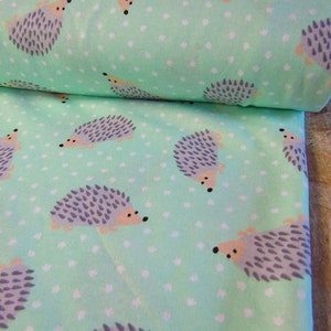 May include: Mint green fabric with a white polka dot pattern and a repeating design of gray hedgehogs.