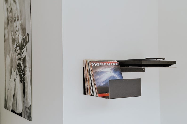 May include: A black metal wall shelf with a record player on top and a stack of vinyl records underneath. The record cover on top reads "MORPHINE".