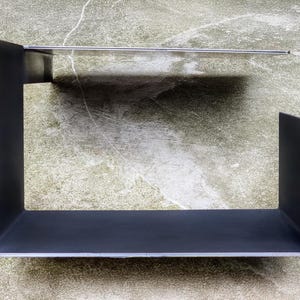 May include: A black metal shelf unit with two shelves. The shelves are rectangular and have a simple, modern design.
