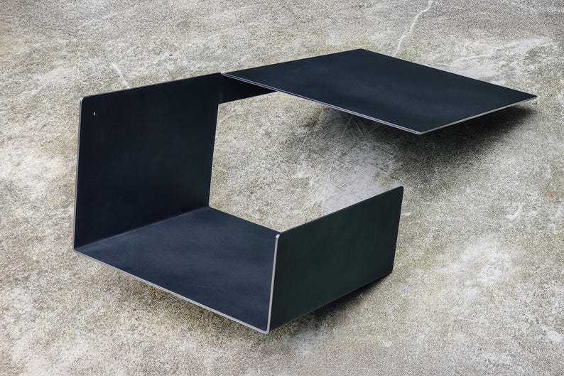 May include: A black metal shelf unit with a removable top panel. The shelf unit is made of metal and has a simple, modern design.