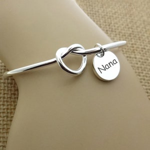 May include: Silver bracelet with a heart-shaped knot and a charm that says "Nana".
