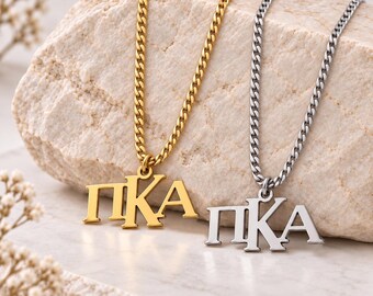 May include: Two necklaces featuring Greek letter pendants that spell Pi Kappa Alpha. One necklace is gold-toned with a matching gold-toned curb chain, and the other is silver-toned with a matching silver-toned curb chain. Both pendants display the letters ΠΚΑ.