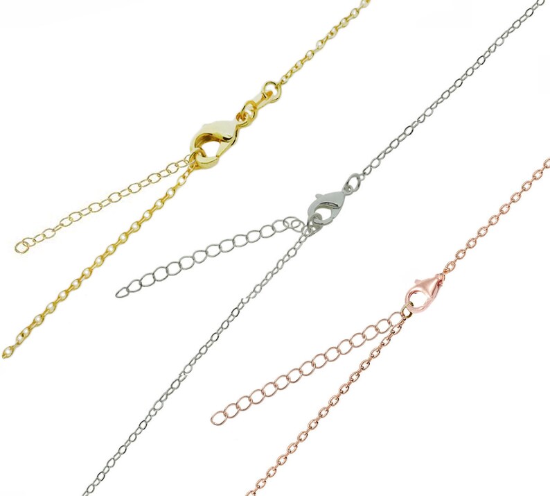 May include: Close-up of three delicate chain necklaces in gold, silver, and rose gold. Each necklace features a lobster clasp and an adjustable chain. The chains are displayed against a white background.