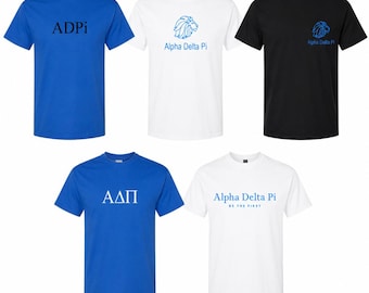 May include: Five short-sleeved crew neck t-shirts in blue, white, and black. Designs include the text ADPi, Alpha Delta Pi with a lion graphic, and the Greek letters ΑΔΠ. One white shirt features the text Alpha Delta Pi Be The First.
