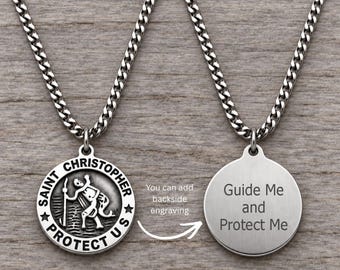 May include: A silver-toned metal Saint Christopher pendant necklace on a curb chain. The front features an embossed figure of Saint Christopher with the text SAINT CHRISTOPHER PROTECT US. The back shows the engraved text Guide Me and Protect Me.