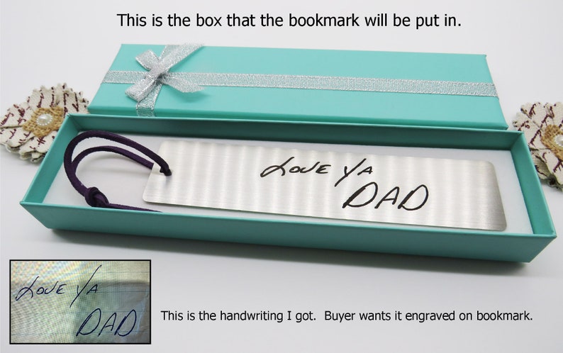 May include: A silver bookmark with a handwritten message "LOVE YA DAD" in a turquoise gift box. The bookmark is in a gift box with a silver ribbon.