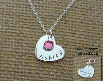 May include: Silver heart necklace with a pink crystal and the name "Ashley" engraved on the front. The back of the heart can be engraved with "First Communion 3-20-22".