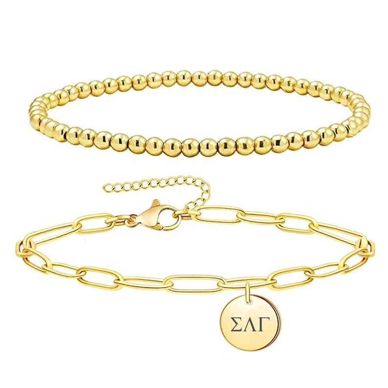 May include: Two gold bracelets. One is a simple beaded bracelet. The other is a chain bracelet with a round charm that says "&Sigma;&Lambda;&Gamma;".