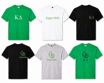 May include: A collection of six short-sleeved t-shirts in green, white, black, and gray. The shirts feature various Kappa Delta designs, including the Greek letters KΔ in white or green, and a green nautilus shell graphic with the text Kappa Delta.