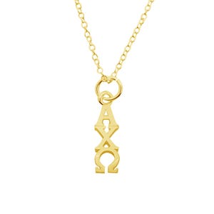 May include: A gold-colored necklace with a pendant featuring the Greek letters Alpha, Chi, and Omega. The pendant is vertically aligned and suspended from a delicate chain. The necklace is displayed against a white background.