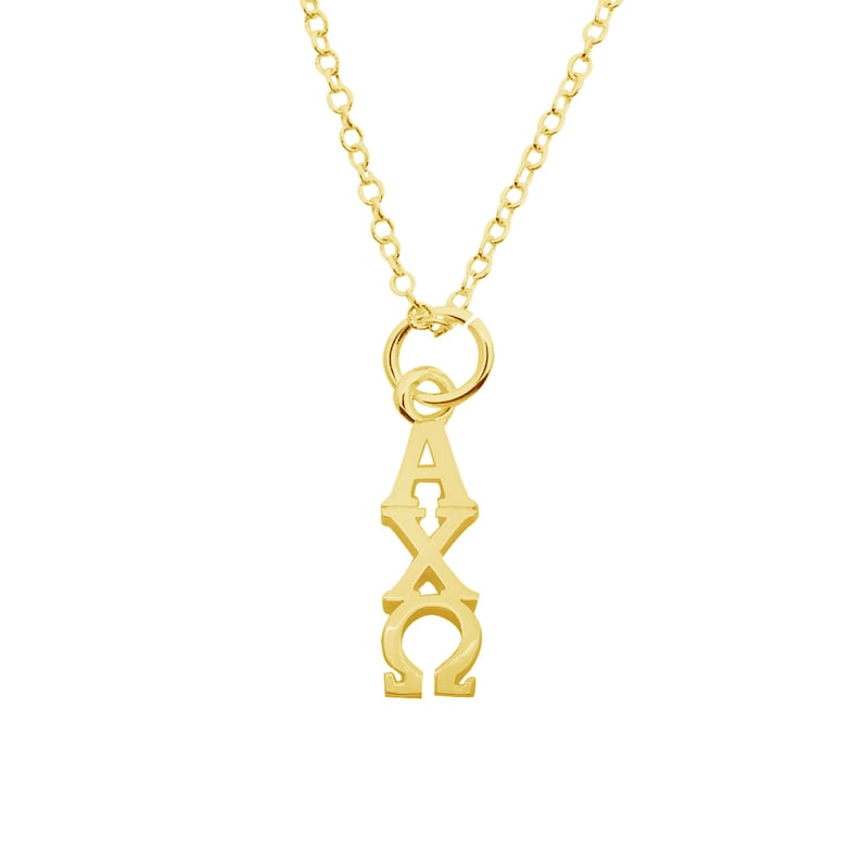 May include: A gold-colored necklace with a pendant featuring the Greek letters Alpha, Chi, and Omega. The pendant is vertically aligned and suspended from a delicate chain. The necklace is displayed against a white background.