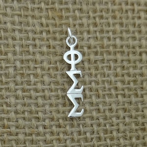 May include: Silver charm with the Greek letters Phi and Sigma stacked vertically.