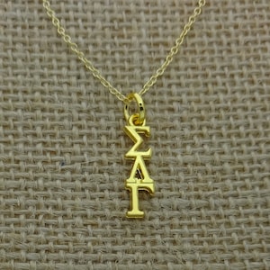 May include: A gold chain necklace with a pendant featuring the Greek letters Sigma, Delta, and Gamma.