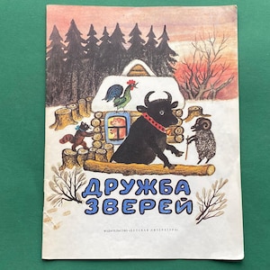 Pode incluir: Uma capa de livro infantil vintage com uma ilustração colorida de animais em um cenário de floresta. O título do livro é "Druzhba Zverei", que se traduz como "Amizade animal".
