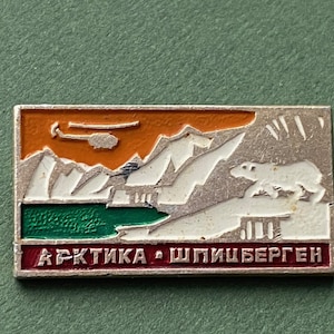 May include: A silver and enamel pin featuring a white polar bear walking on a snowy mountain range. The background is orange and green, with the text "АРКТИКА - ШПИЦБЕРГЕН" at the bottom.