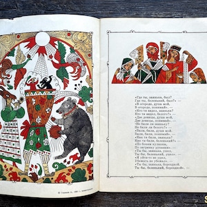 Op de afbeelding: Een open boek met een kleurrijke illustratie van een beer, een persoon met een masker en figuren in traditionele kleding op de linkerpagina, met een kleinere illustratie van vier personen en Russische tekst op de rechterpagina binnen een kader.