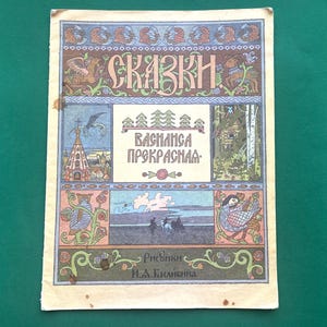 Puede incluir: Portada de libro ilustrada vintage con el título "SKAZKI" en letras ornamentadas. La portada presenta ilustraciones coloridas de una iglesia, un bosque y figuras, con texto en ruso. La obra de arte está enmarcada por bordes decorativos.