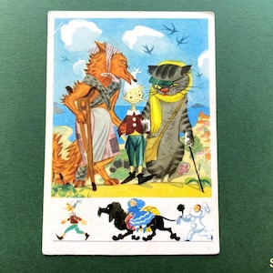 Op de afbeelding: Een vintage ansichtkaartillustratie met een vos met een kruk, een houten pop en een grijze cyperse kat met een gele sjaal. Hieronder toont een kleinere scène de lopende pop, een zwarte hond met een blauwe ruiter en een wit figuur.
