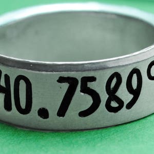 Puede incluir: Un anillo de plata con la inscripción "40.7589° N" grabada en él.