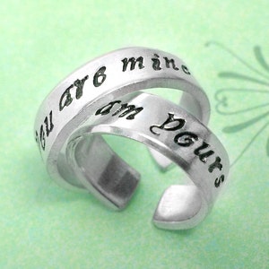 May include: Two silver rings with the words "You are mine" and "I'm yours" engraved on them.