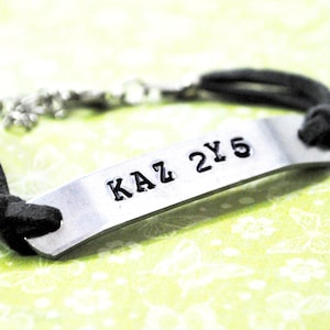 KAZ2Y5. Hand Stamped Aluminum ID tag on Grey Suede Cord. Supernatural Inspired